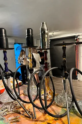 Row of prepared hookahs with black hoses on a table at an indoor event